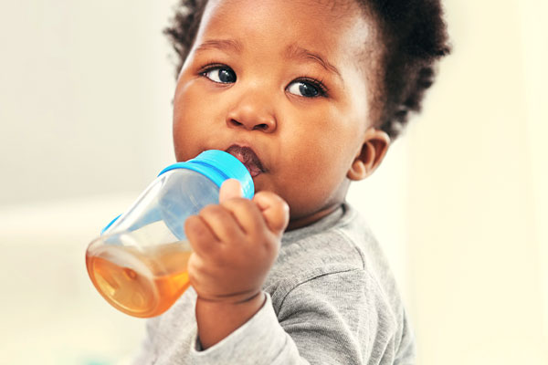 نوزاد در حال خوردن آبمیوه در شیشه شیر